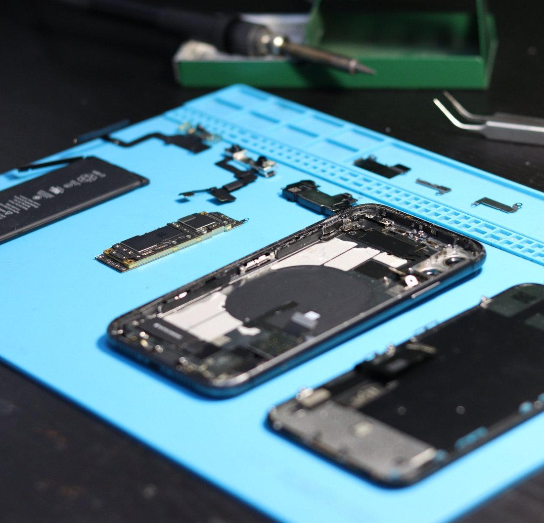Smartphone démonté pièce par pièce sur un tapis de réparation